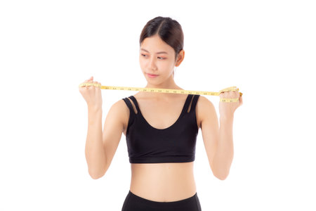 Portrait happy young asian woman in sportswear holding measure tape isolated white background, girl care body with workout or exercise, dieting and cellulite, sport and loss weight for health.の写真素材