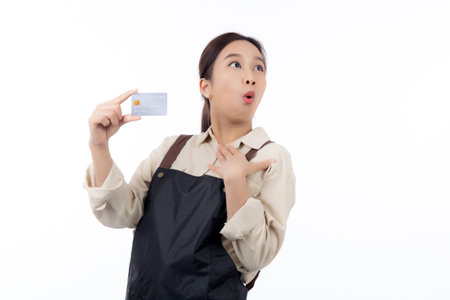 Portrait happiness young asian woman wearing apron holding credit card isolated white background, barista or waitress showing debit card for purchase or shopping online and payment, small business.の写真素材