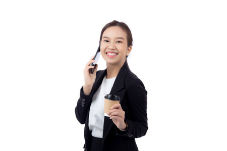 Portrait cheerful young asian businesswoman holding coffee cup while talking smart phone with relax and satisfied isolated white background, business woman drinking coffee and speaking on smartphone.の写真素材