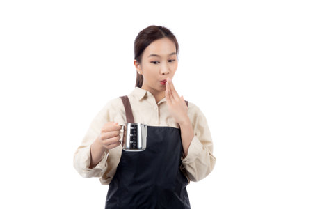 Portrait young asian woman barista work happy holding milk jug pour in coffee cup isolated white background, joyful barista wearing apron holding pitcher and coffee cup, small business or startup.の写真素材