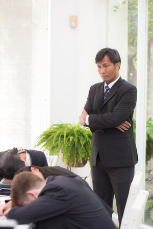 Business team meeting with frustrated boss while exhausted employee in modern office, stress boss and upset while business people concerned and sleep in office, business and teamwork with conflict.の写真素材