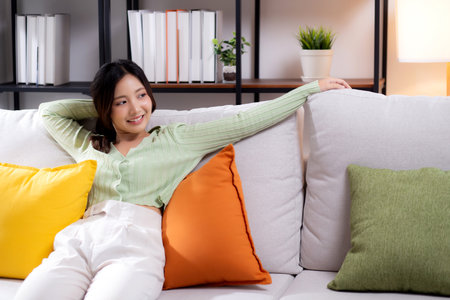 Happy young asian woman relax and leisure sitting on sofa in living room at home, happiness girl with calm on couch with cheerful, woman rest with cozy, one person, lifestyle concept.の写真素材