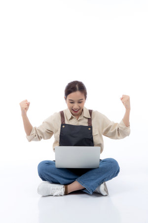 Portrait young asian business woman wearing apron holding laptop computer isolated white background, waitress or barista holding laptop computer with success, cut out, business or freelance.の写真素材