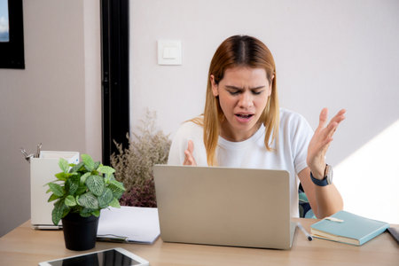 Unhappy young caucasian businesswoman using laptop computer on desk with stress and burnout at home office, business woman working on laptop with frustrated and anxiety, business and expression.の写真素材