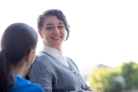 Young caucasian nurse comforting with patient while sitting on wheelchair in outdoor park, doctor...