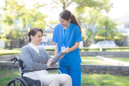 Young caucasian nurse therapy with patient while stretching muscle hand in outdoor park, doctor woman support and rehabilitation with patient, caregiver and service with woman, medical and rheumatism.の写真素材