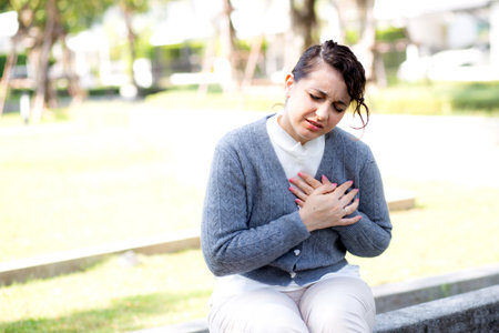 Caucasian woman chest pain in outdoor park, emergency of patient with injury, urgency and disease of woman, medical and accident, sick of patient and expression, medical and health, one person.の写真素材
