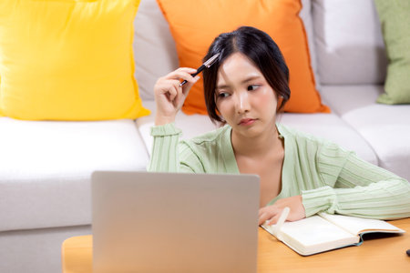 Young asian woman planning and strategy about finance and investment or tax while thoughtful in living room at home, woman with expense and budget while thinking of home, business and finance.の写真素材