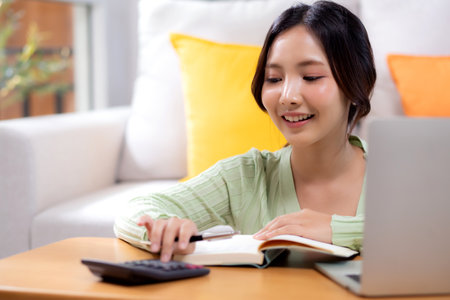 Young asian woman planning and strategy about finance and investment or tax while calculate on calculator in living room at home, woman with expense and budget of home, business and finance.の写真素材