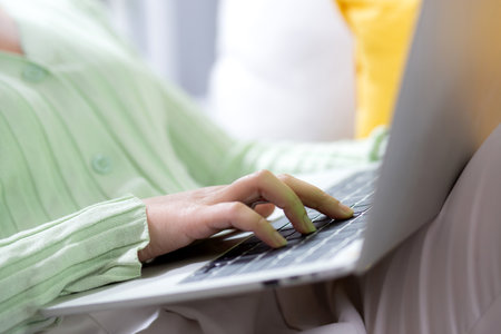 Closeup hands young woman sitting on sofa using laptop computer working from home in the living room at home, female is freelance using notebook online, one person, business and lifestyles concept.の写真素材