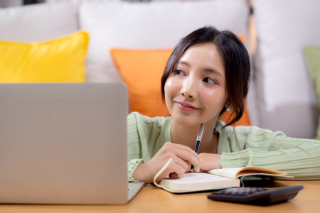 Young asian woman planning and strategy about finance and investment or tax while thoughtful in living room at home, woman with expense and budget while thinking of home, business and finance.の写真素材