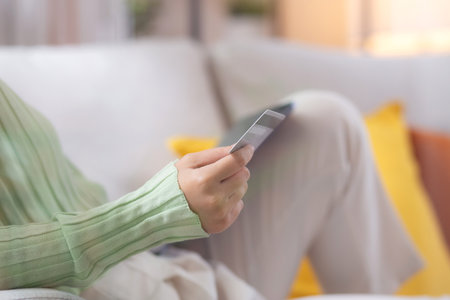 Young asian woman sitting on sofa using tablet computer shopping online with credit card buying to internet while cheerful, female payment with business, purchase and payment, business and finance.の写真素材