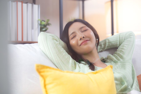 Happy young asian woman relax and leisure sitting on sofa in living room at home, happiness girl sleeping with calm on couch, woman napping and rest with cozy, one person, lifestyle concept.の写真素材