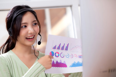 Young asian businesswoman sitting video call for presenting finance in home office, happiness business woman conference with remote distant about finance on desk, small business and meeting online.の写真素材