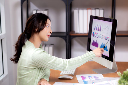 Young asian businesswoman planning and strategy about finance looking graph and chart of report marketing in home office, business woman analyzing financial and revenue for success, business concept.の写真素材