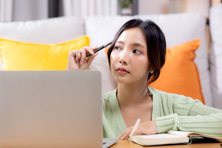 Young asian woman planning and strategy about finance and investment or tax while thoughtful in living room at home, woman with expense and budget while thinking of home, business and finance.の写真素材