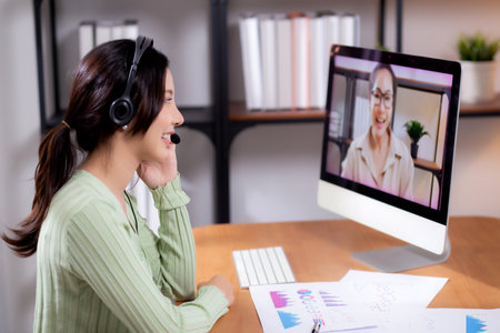 Young asian businesswoman sitting video call for interview in modern home office, happiness business woman conference with remote distant about finance on desk, small business and meeting online.の写真素材