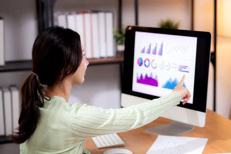 Young asian businesswoman planning and strategy about finance looking graph and chart of report marketing in home office, business woman analyzing financial and revenue for success, business concept.の写真素材