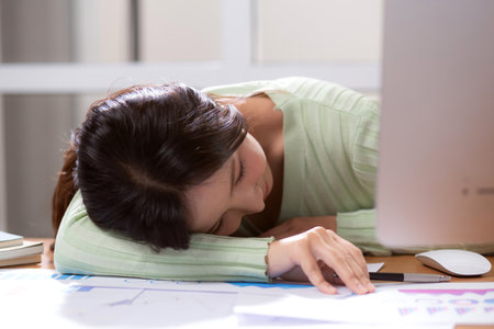 Young asian businesswoman exhaustion and sleep while overworked in home office, business woman fatigue and burnout, woman nap and lying down on desk while working in home office.の写真素材