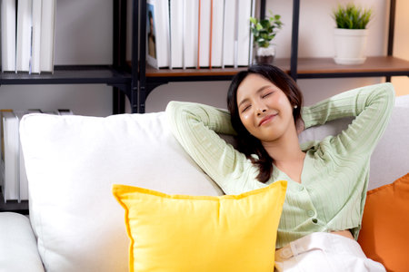 Happy young asian woman relax and leisure sitting on sofa in living room at home, happiness girl sleeping with calm on couch, woman napping and rest with cozy, one person, lifestyle concept.の写真素材