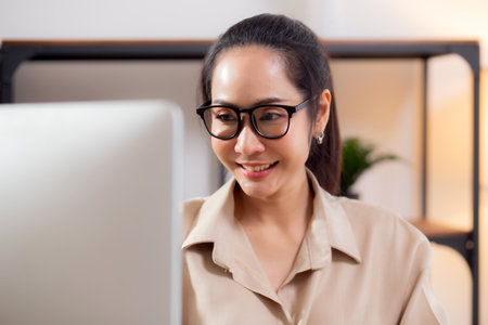Happiness young businesswoman using desktop computer on desk in living room at home office, business woman using computer for surfing internet, entrepreneur or freelance, business and communication.の写真素材