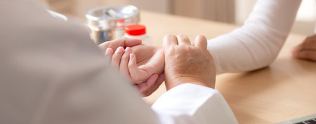 Senior woman doctor examining elderly while holding arm for pulse sitting in modern medical office, doctor checkup patient, patient and insurance, medical and health, doctor discussing with patient.の写真素材