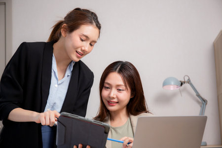Two young business woman working together about project for success in modern office, businesswoman discussion with consulting for planning and analyzing about marketing, business and strategy.の写真素材