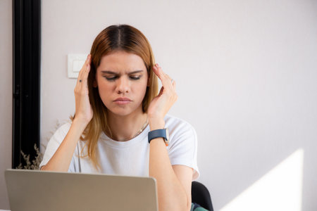 Unhappy young caucasian businesswoman using laptop computer on desk with stress and burnout at home office, business woman working on laptop with frustrated and anxiety, business and expression.の写真素材