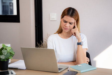 Unhappy young caucasian businesswoman using laptop computer on desk with stress and burnout at home office, business woman working on laptop with frustrated and anxiety, business and expression.の写真素材