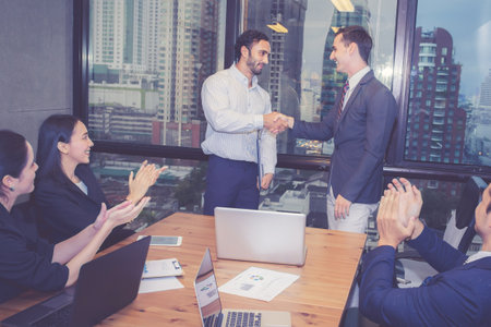 Group business team meeting about agreement with success while shaking hands for celebrating in modern office, businessman handshake with partner after negotiation for achievement about project.の写真素材