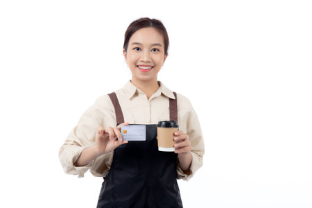 Portrait happiness young asian woman wearing apron holding credit card isolated white background, barista or waitress showing debit card for purchase or shopping online and payment, small business.の写真素材