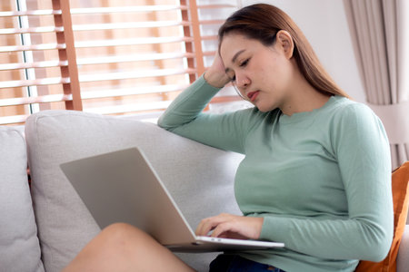 Young asian businesswoman working laptop with stress and frustrated in living room at home, business woman using on notebook with upset and tired, expression and emotion, business and lifestyle.の写真素材