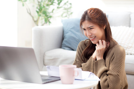 Young asian woman using laptop with happy and satisfaction in living room at home, woman relaxation with notebook computer or working from home, business browsing email, business and freelance.の写真素材