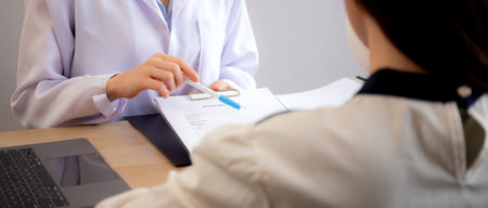 Young asian patient woman consulting with doctor in coat about wrinkle and skin for rejuvenate and beauty while looking document in modern medical office, doctor explaining and diagnostic facial.の写真素材