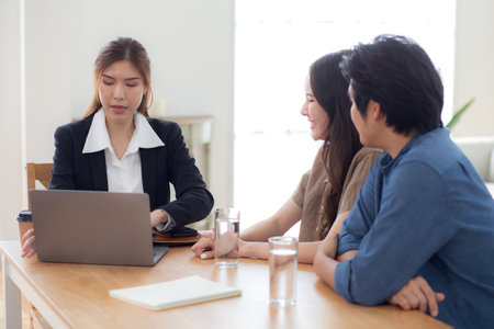 Happy asian couple discussion with real estate agent or insurance agent for investment in home office, mortgage loan or property purchase home, sale explaining insurance plan with couple.の写真素材