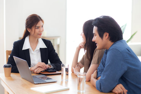 Happy asian couple discussion with real estate agent or insurance agent for investment in home office, mortgage loan or property purchase home, sale explaining insurance plan with couple.の写真素材
