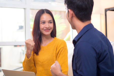 Young asian couple looking on laptop for relax with cozy and success sitting on sofa in living room at home, couple leisure watching laptop on couch, relationship and bonding, lifestyle concept.の写真素材