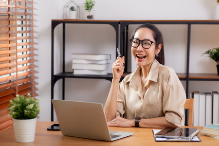 Young asian business woman using laptop for success in modern home office, businesswoman working with laptop computer gesture glad in living room at home, business and freelance concept.の写真素材