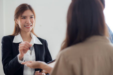 Happy asian couple receiving house key from real estate agent after success property purchase home, home ownership and mortgage loan, investment and mortgage, couple consulting with real estate agent.の写真素材