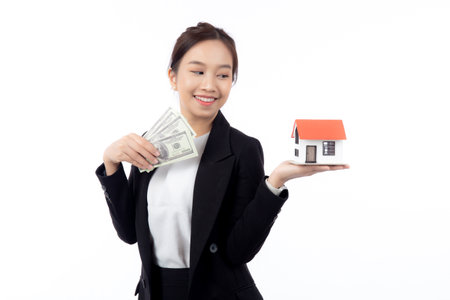 Portrait young asian businesswoman holding house and money for mortgage isolated white background, agent insurance business woman holding home for investment and presenting, business and finance.の写真素材