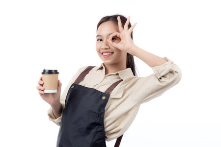 Portrait young asian woman barista holding a takeaway coffee cup with excited gesture ok isolated white background, happy barista presenting takeaway coffee with success, small business or startup.の写真素材