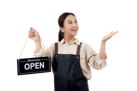 Portrait young asian barista woman wearing apron holding open sign for inviting customer to enter with happiness, waitress woman holding signboard with open, small business or startup business.の写真素材