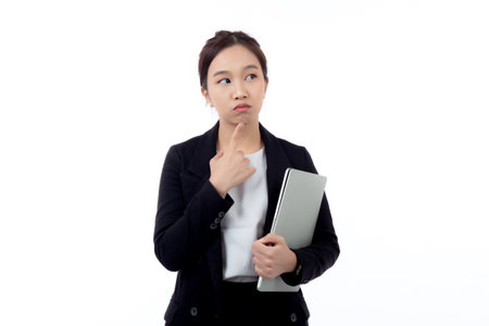 Portrait young asian business woman standing holding laptop computer and thoughtful isolated on white background, businesswoman in suit holding notebook while thinking, marketing and communication.の写真素材