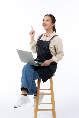 Portrait young asian business woman wearing apron holding laptop computer isolated white background, waitress or barista holding laptop computer with success, cut out, business or freelance.の写真素材