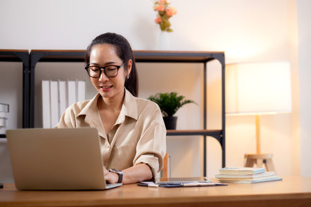 Happiness young businesswoman using laptop computer on desk in living room at home office, business woman using laptop for surfing internet, entrepreneur or freelance, business and communication.の写真素材