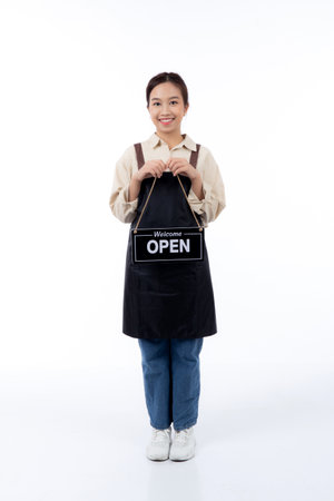 Portrait young asian barista woman wearing apron holding open sign for inviting customer to enter with happiness, waitress woman holding signboard with open, small business or startup business.の写真素材