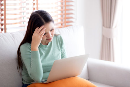 Young asian businesswoman working laptop with stress and frustrated in living room at home, business woman using on notebook with upset and tired, expression and emotion, business and lifestyle.の写真素材