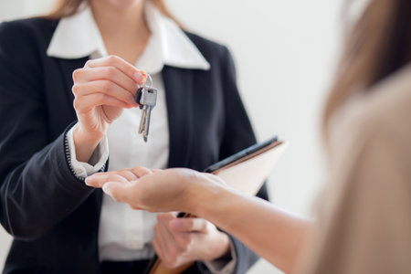 Closeup hands real estate agent giving house key with couple after success property purchase home, home ownership and mortgage loan, investment and mortgage, couple consulting with real estate agent.の写真素材