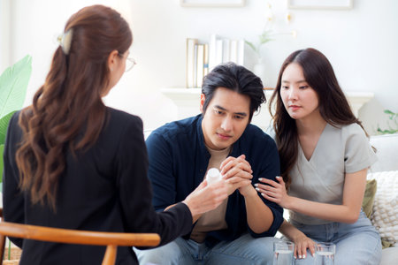 Asian couple counseling of therapist for support and guidance about depression with stress and worry, psychiatrist healing couple with problem mental health with explaining medical and health.の写真素材