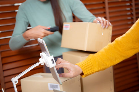 Closeup hand woman live online while scanning package with barcode reader in office, online seller, shipping and express, distribution and logistic, retail and shipment, business and delivery online.の写真素材